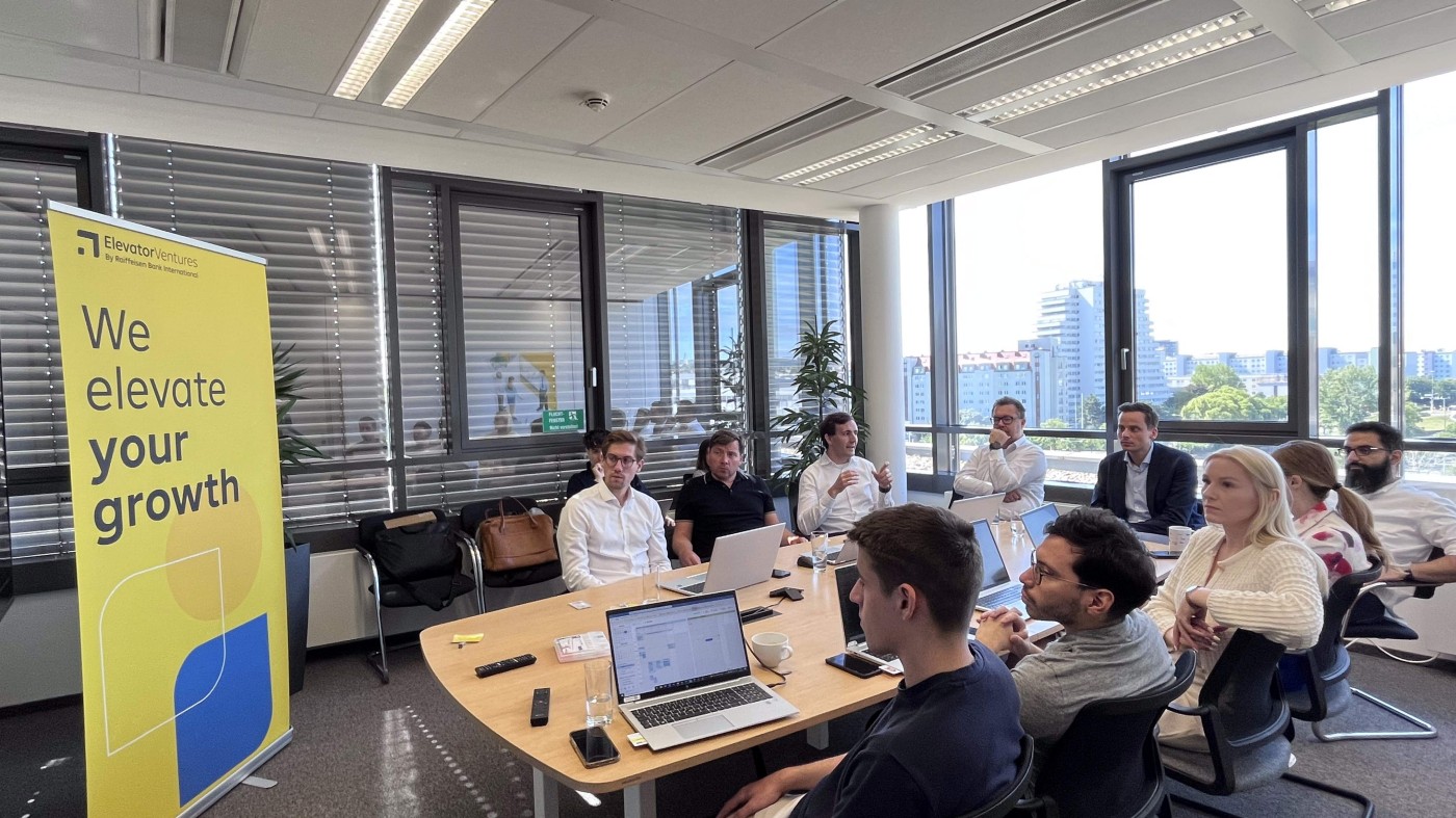 Group of ten people listening to a presentation around a table